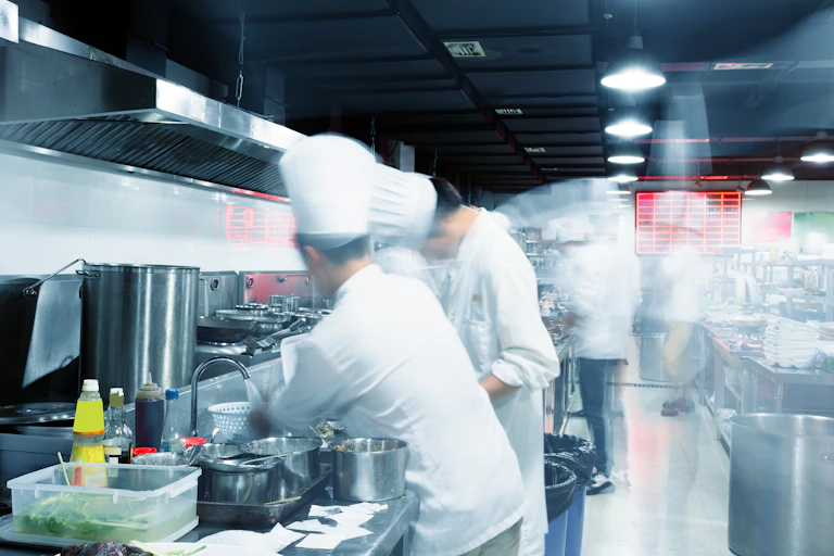 Busy chefs seen blurred working in a commercial kitchen