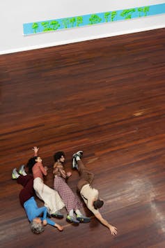 Four dancers lie on the floor.