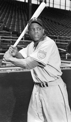 A Black man gets ready to swing a baseball bat.