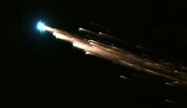 Photo showing several burning fragments of a satellite falling through the sky.