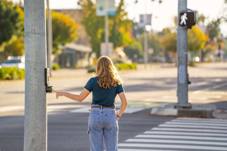 Young woman about to cross the street