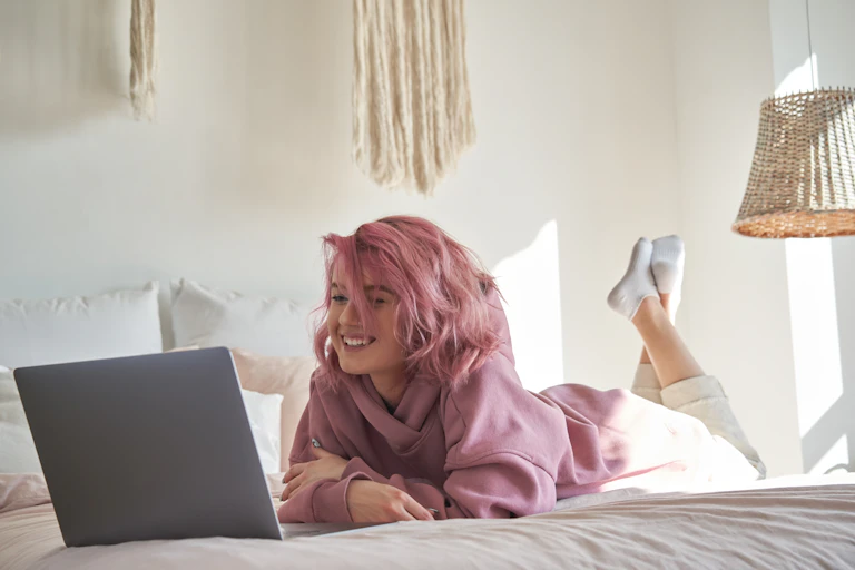 A teenager watches something on her laptop