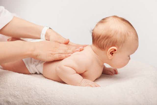 Chiropractor massaging baby's back