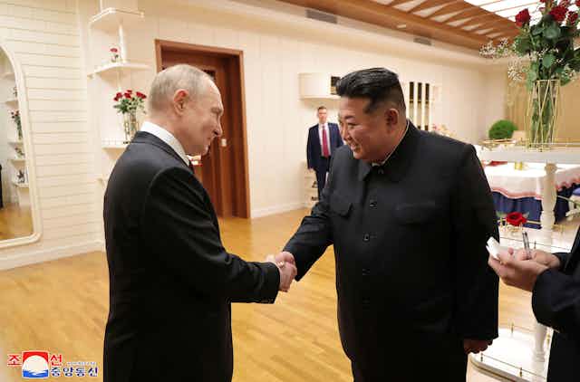 Vladimir Putin and Kim Jung Un shake hands at a June 2024 meeting.