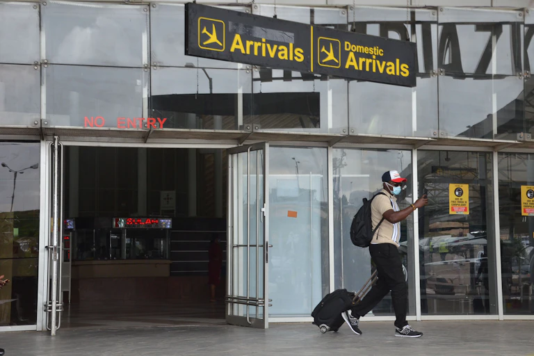 A man wearing a backpack and pulling a travel bag.