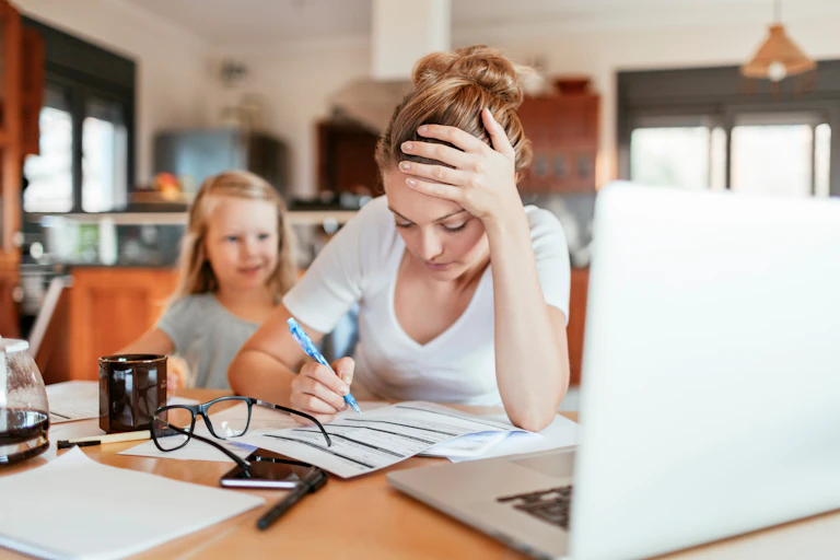 Une mère fatiguée télétravail avec une enfant derrière elle