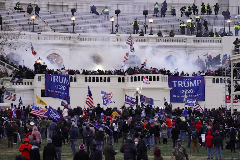 A large white building and protesters on a balcony.