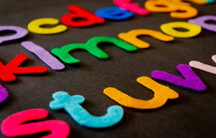 Coloured felt alphabet letters on a black background.