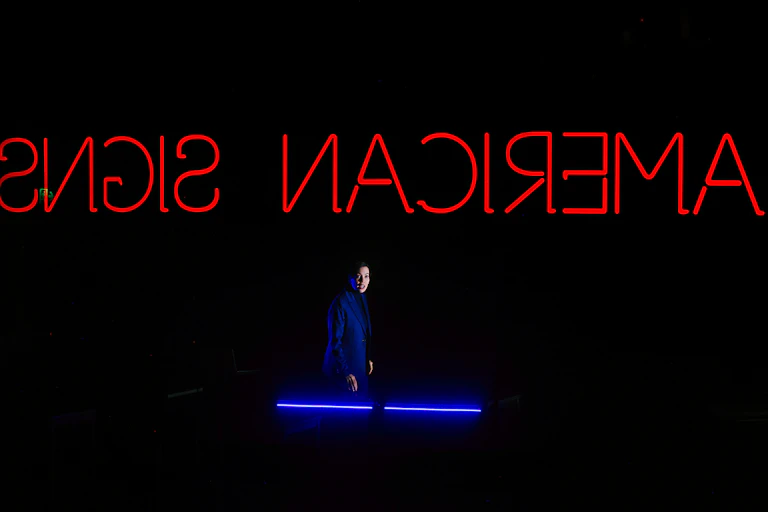 A woman on stage, text reads backwards: American Signs