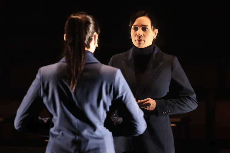 A woman looks into a mirror.