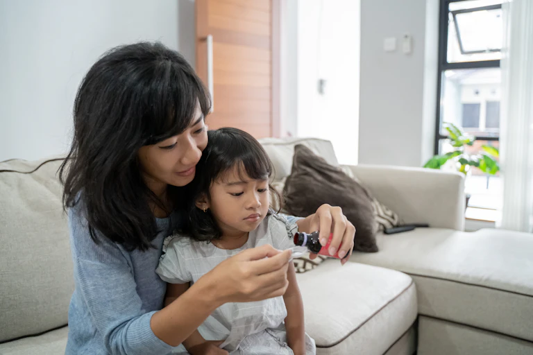 A mother pours out a syrup medicine for her daughter.