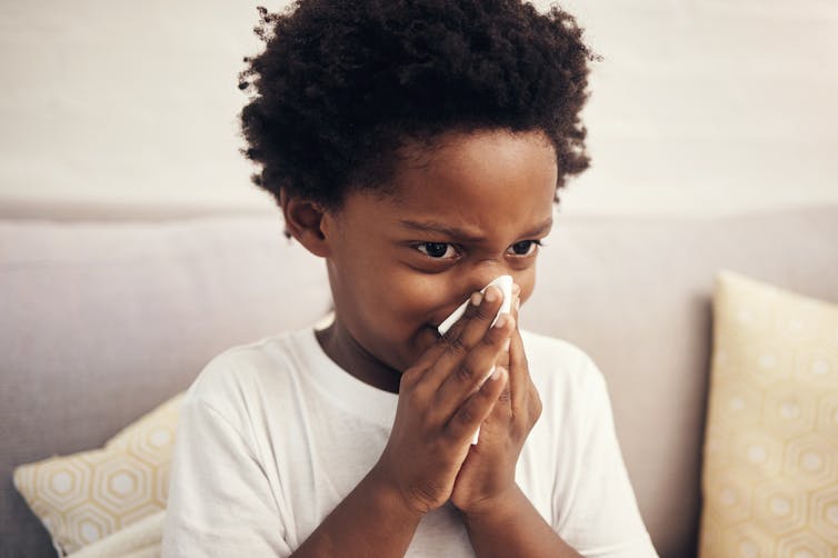 A boy blows his nose.