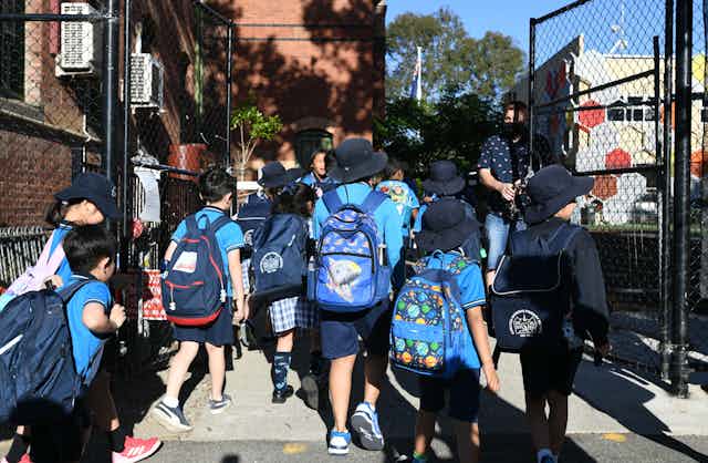 Primary school students walk into the school gates. 