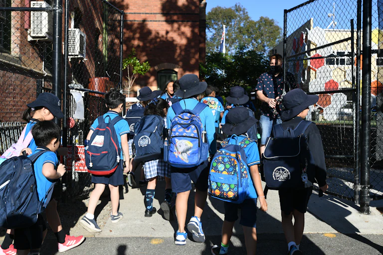 Primary school students walk into the school gates.