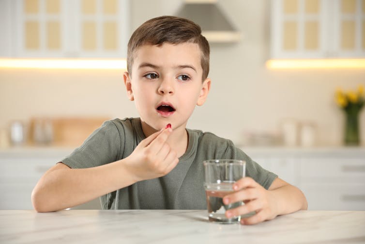A boy putting a pill in his mouth.