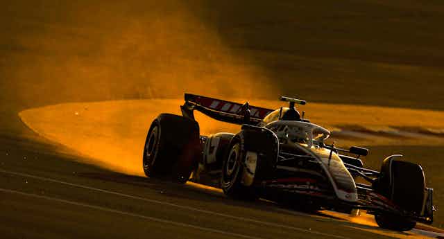 A Formula One car spits out fumes as it turns a corner