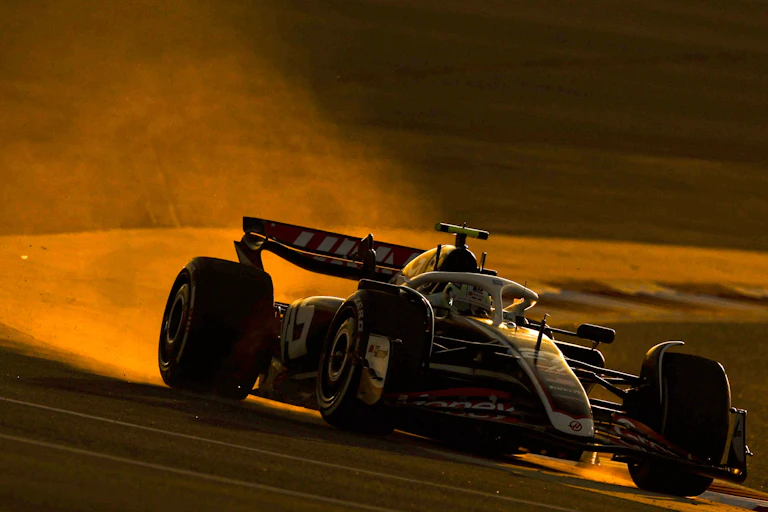 A Formula One car spits out fumes as it turns a corner