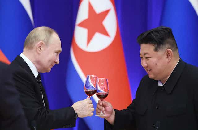 Russian president, Vladimir Putin, and Norther Korean leader, Kim Jong-un, smile as they clink glasses.