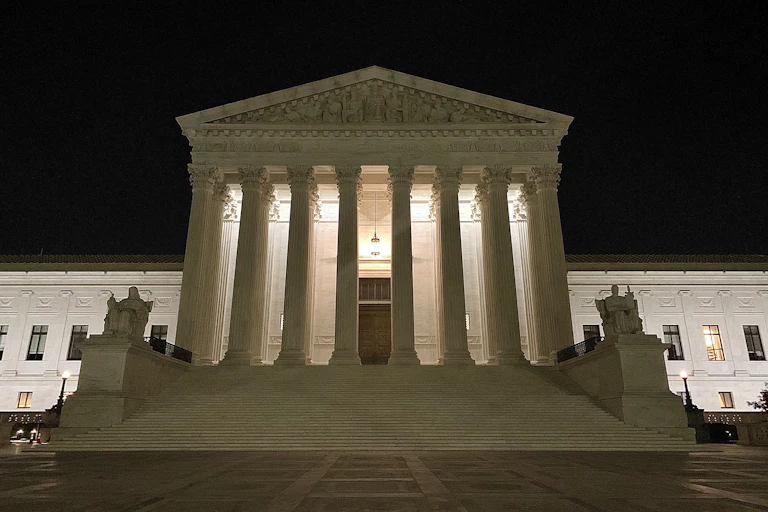 A large white, pillared building set against a dark sky.