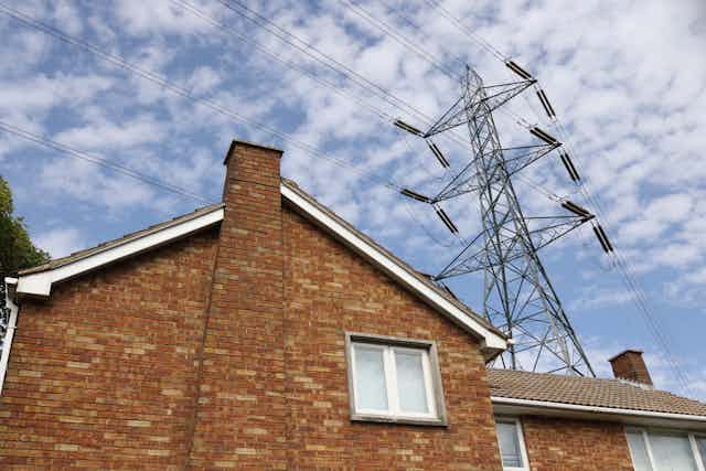 An electricity pylon towers over a house.