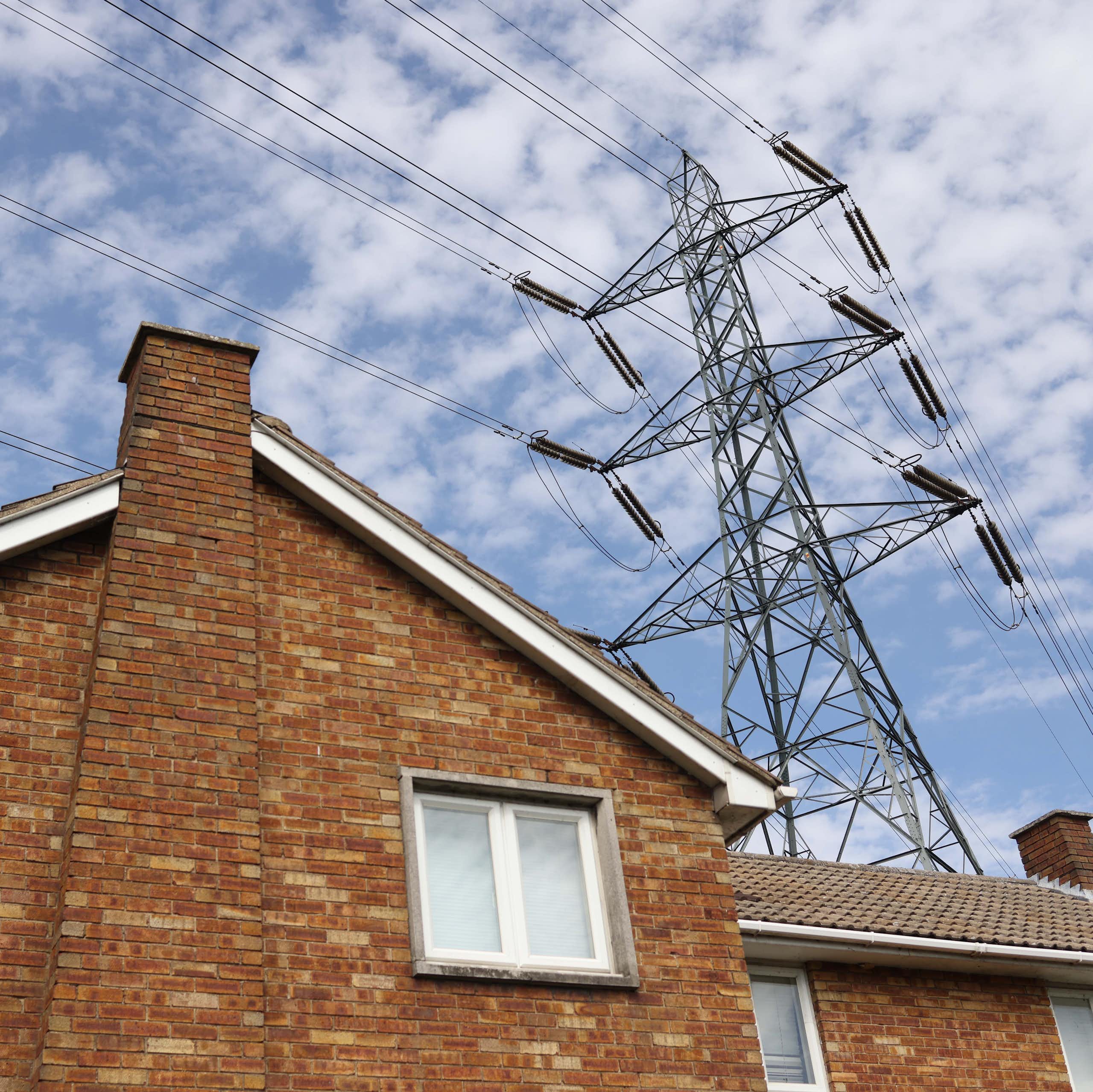 An electricity pylon towers over a house.