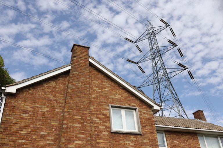 An electricity pylon towers over a house.