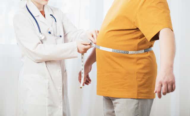 A doctor uses a measuring tape to measure a patient's stomach.