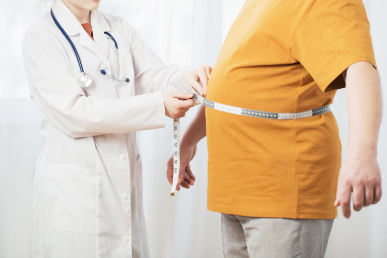 A doctor uses a measuring tape to measure a patient's stomach.