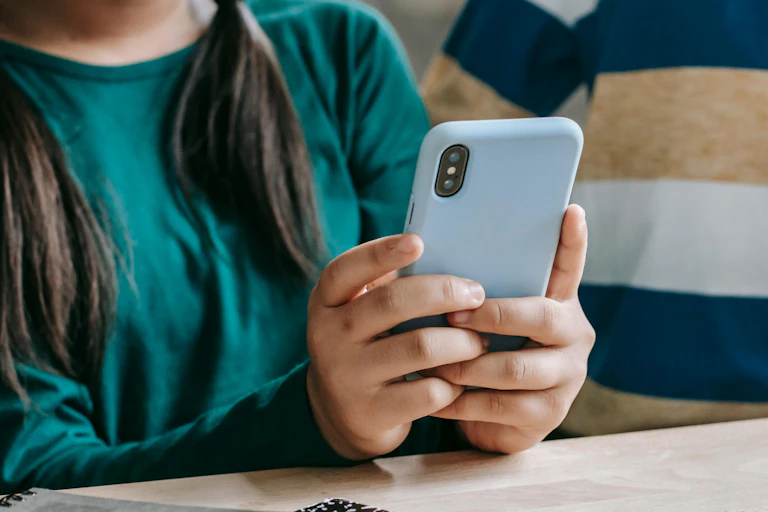 A child's hands seen holding a smartphone next to another child.
