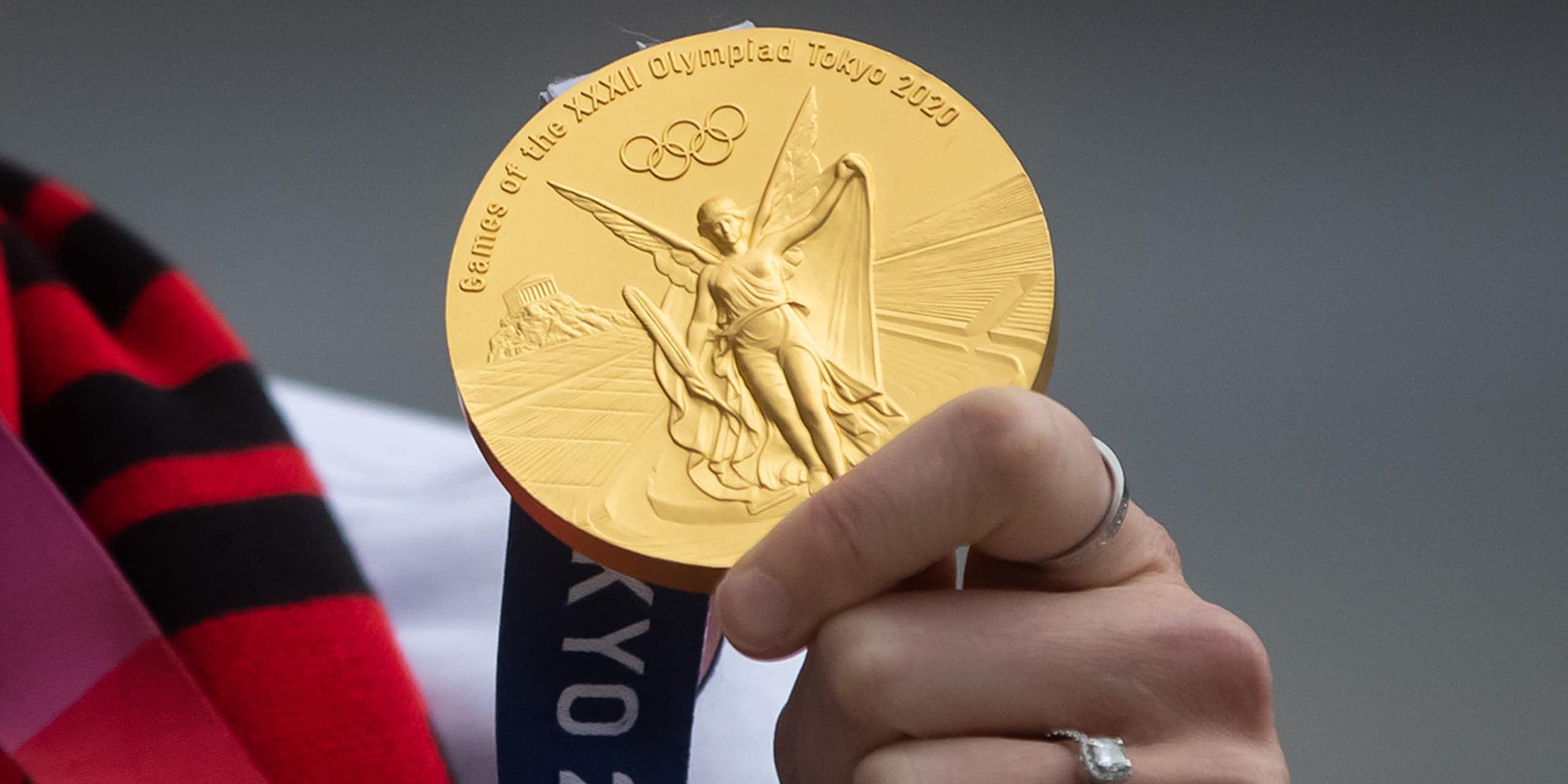 Close up of a hand holding up a gold medal from the Tokyo 2020 Olympics