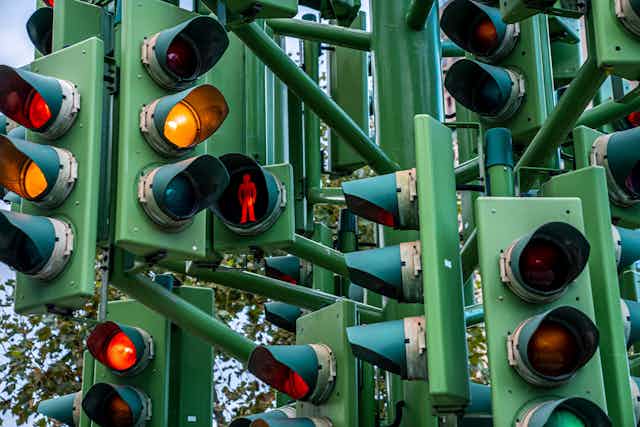 close up of complex system of multiple traffic lights, different coloured lights lit up
