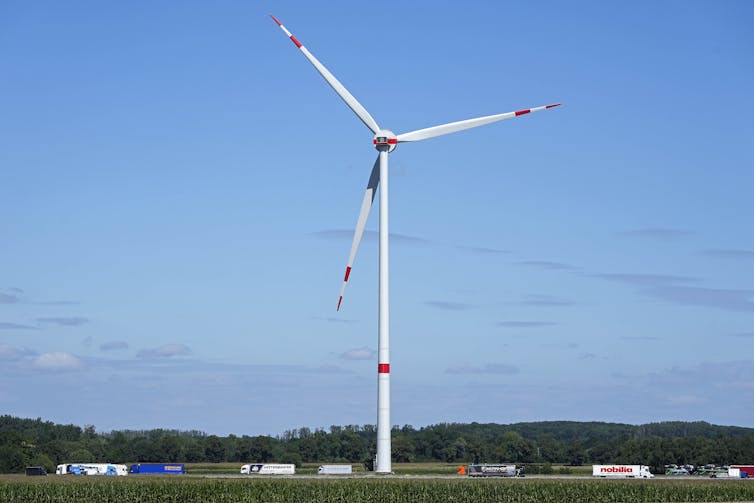 A wind turbine stands over a road.