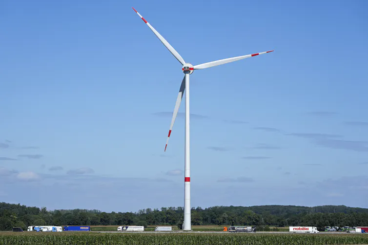 A wind turbine stands over a road.