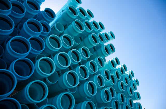 A stack of blue plastic water pipes under a blue sky