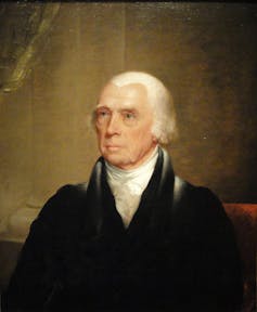 A portrait of a man with white hair, a white high collar shirt and a black jacket.