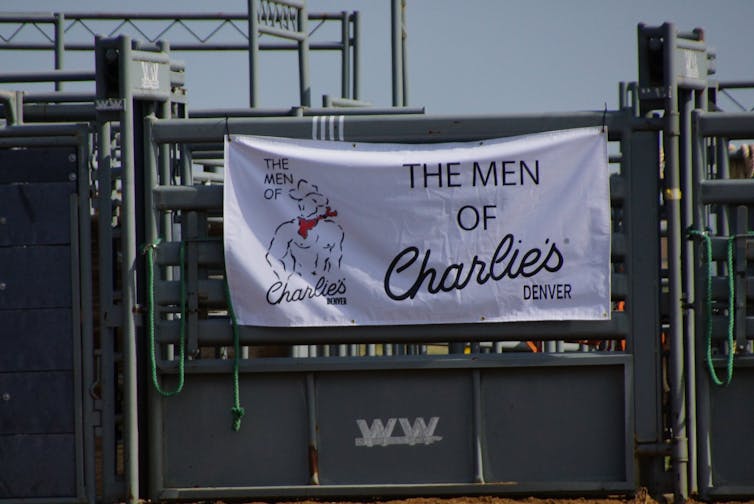 A white advertising banner reading “The Men of Charlies” hung on the rodeo slides.