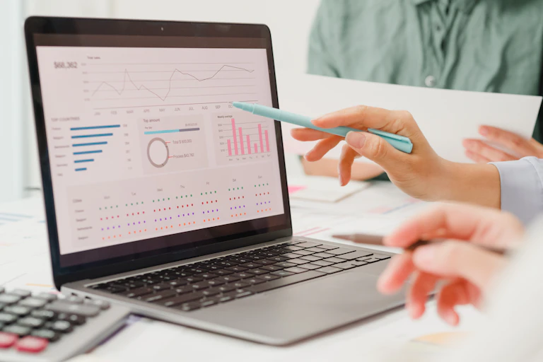A laptop displaying charts and graphs is seen in close-up.