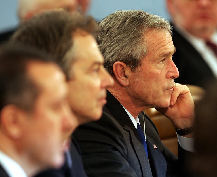 Three men sit side by side.