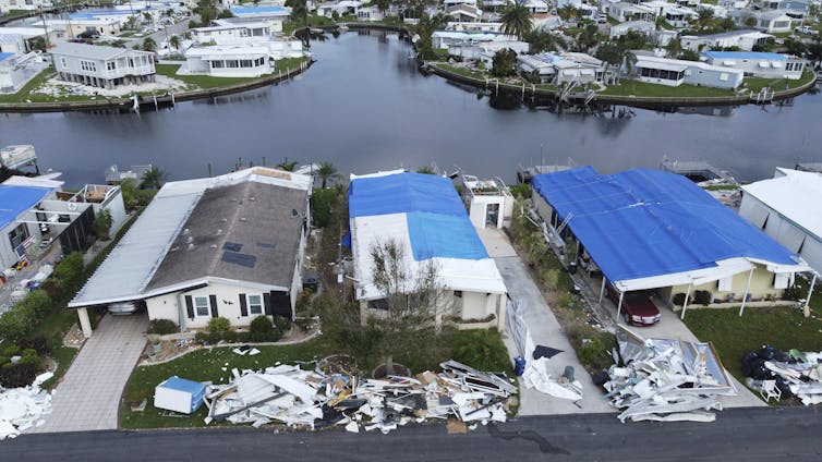 Behind a row of houses destroyed by the hurricane, a canal swollen by floodwaters can be seen threateningly.