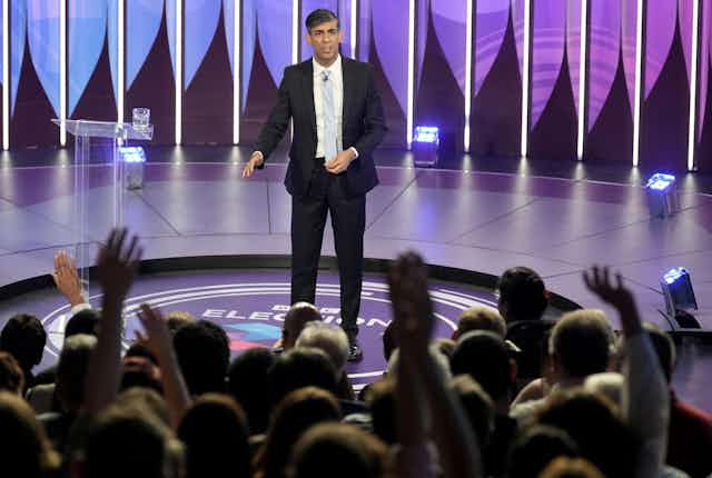 RIshi Sunak in a TV studio in front of an audience raising their hands. 