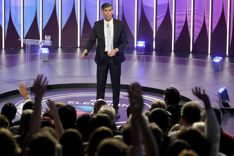 RIshi Sunak in a TV studio in front of an audience raising their hands.