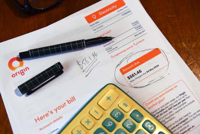 A residential electricity bill, calculator and pen circling the amount due.