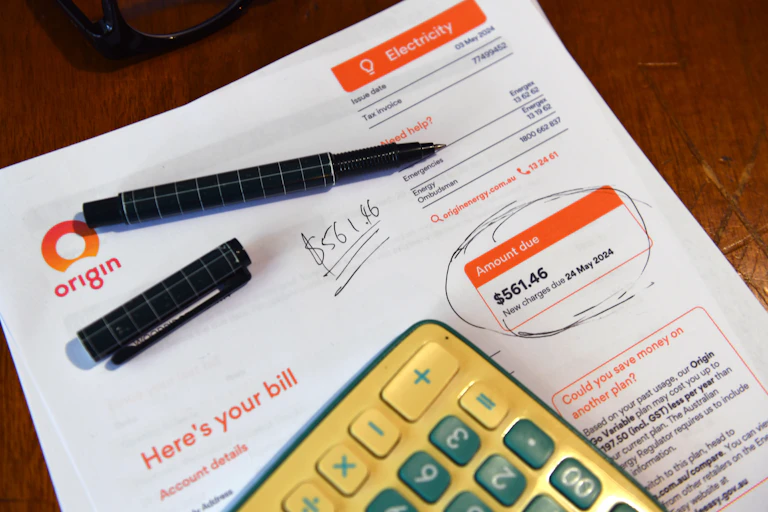 A residential electricity bill, calculator and pen circling the amount due.