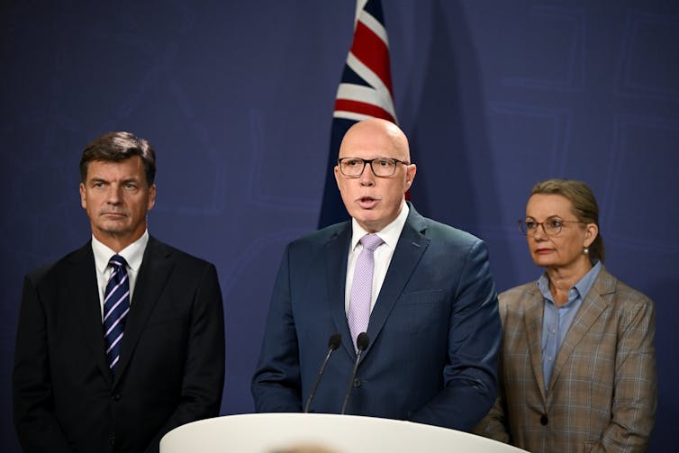 two men and a woman standing at lectern