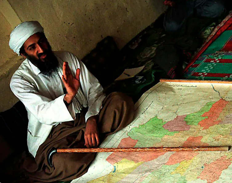 Osama bin Laden sitting in front of a map