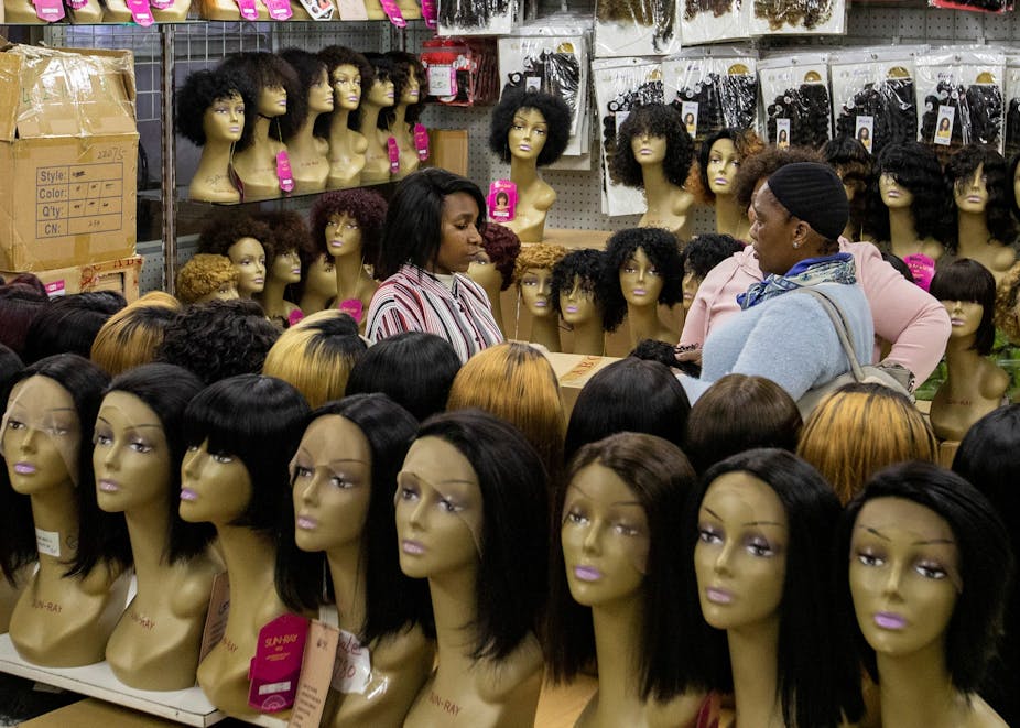 A lady purchases wigs in a shop.