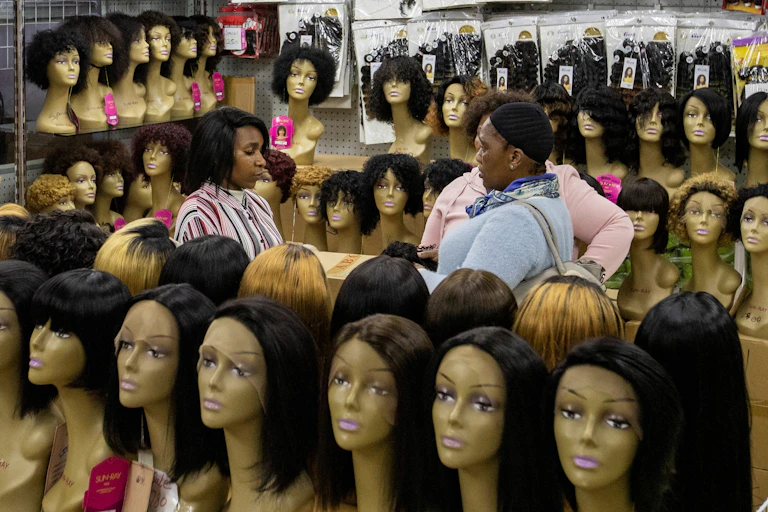 A lady purchases wigs in a shop.