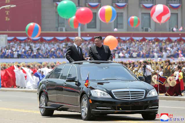 Kim Jung Un and Vladimir Putin in an open top car.