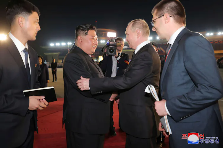 Kim Jung Un and Vladimir Putin shake hands.