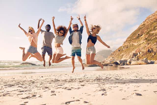 Happy young people jumping on the beach.